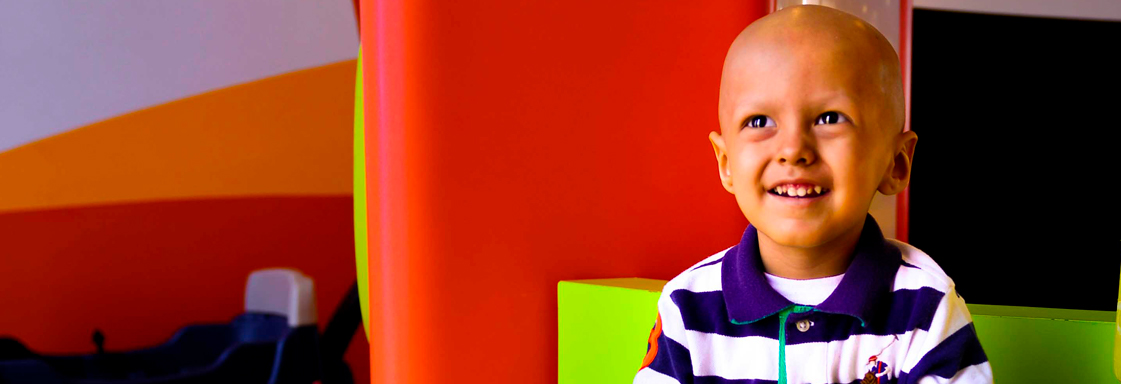 Niño sin cabello sonríe mirando al cielo en los pasillos del HITO